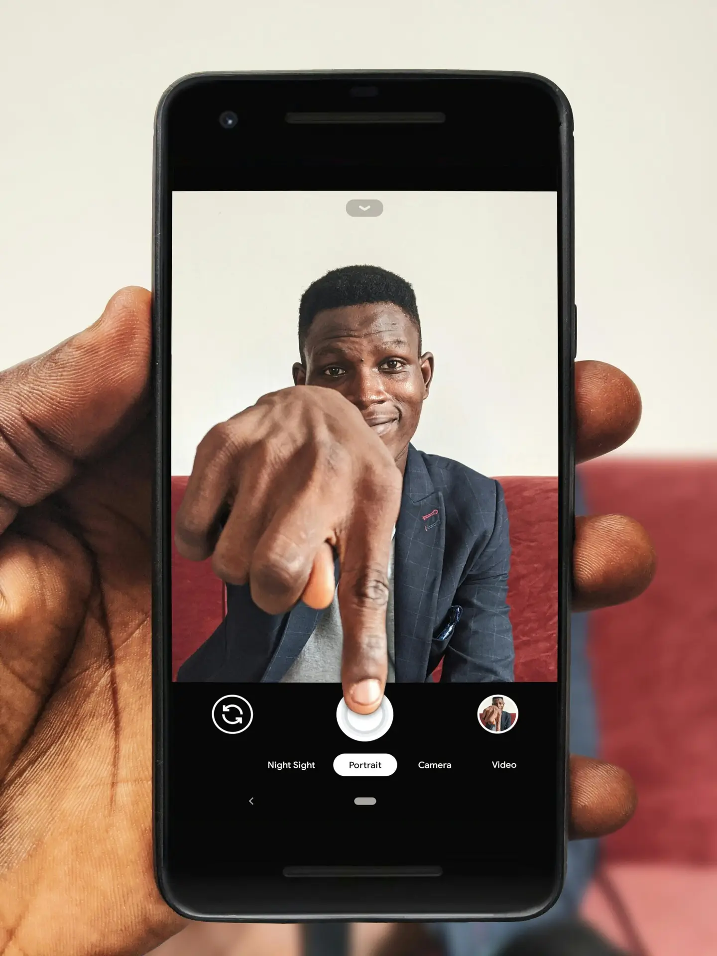 Portrait of a man using a smartphone to take a selfie indoors.