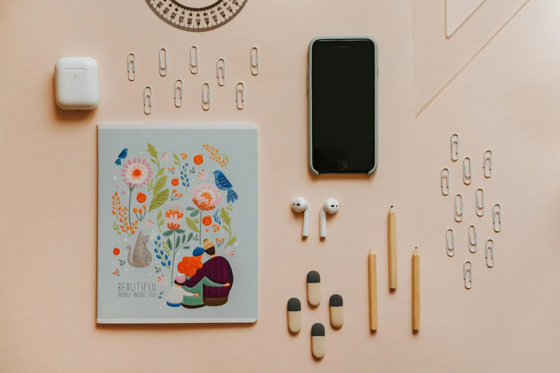 A neatly arranged flat lay of stationery items and gadgets on a pastel surface.